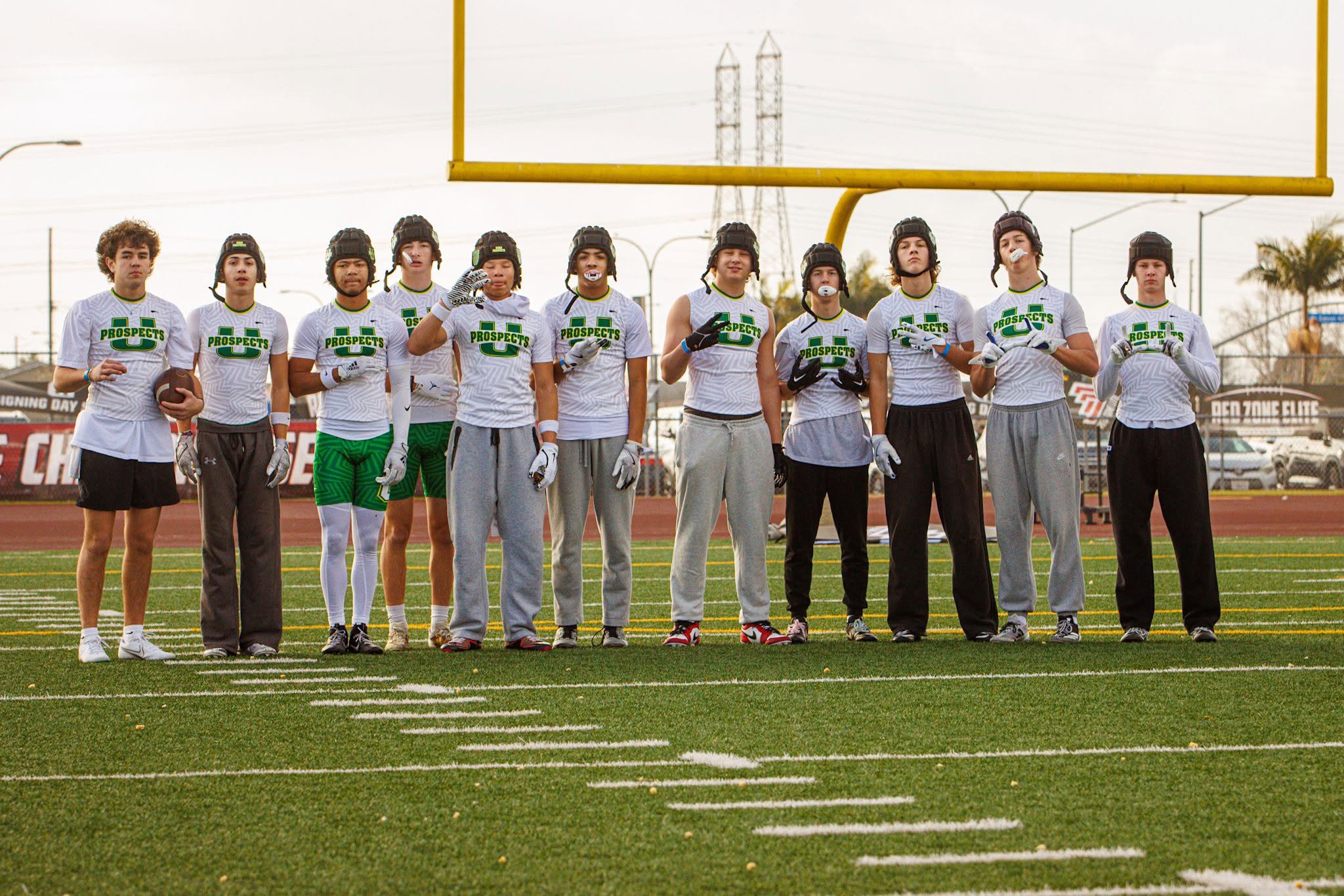 Eleven Utah Prospects players in white jerseys lined up under the goalpost before a tournament game